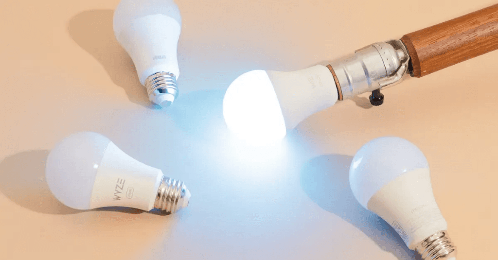 Various smart LED bulbs displayed with traditional lamp fixture