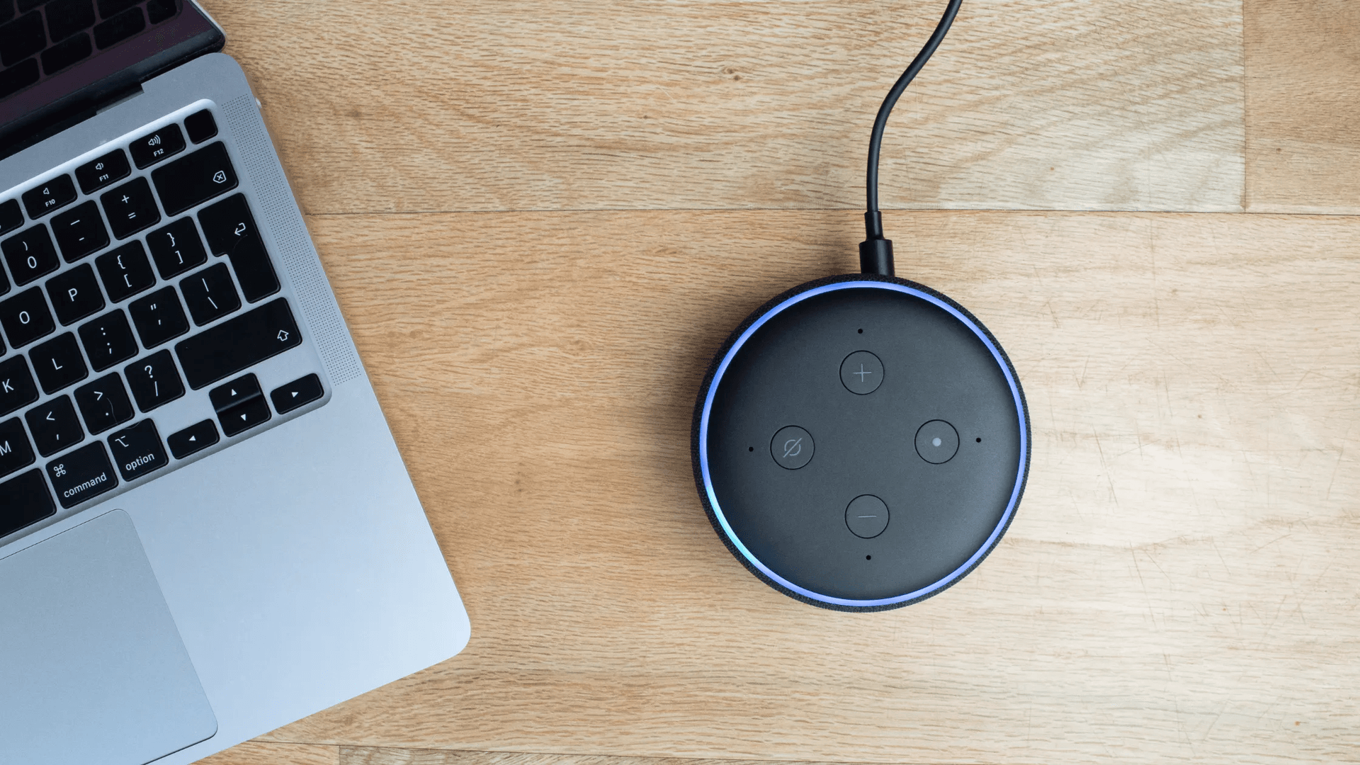 Amazon Alexa smart speaker resting beside a laptop keyboard